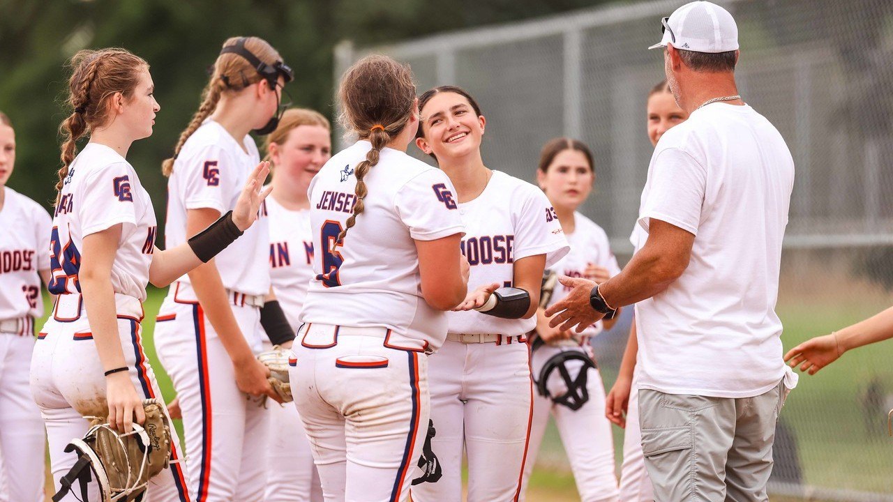 Softball players gathered around their coach during a training session